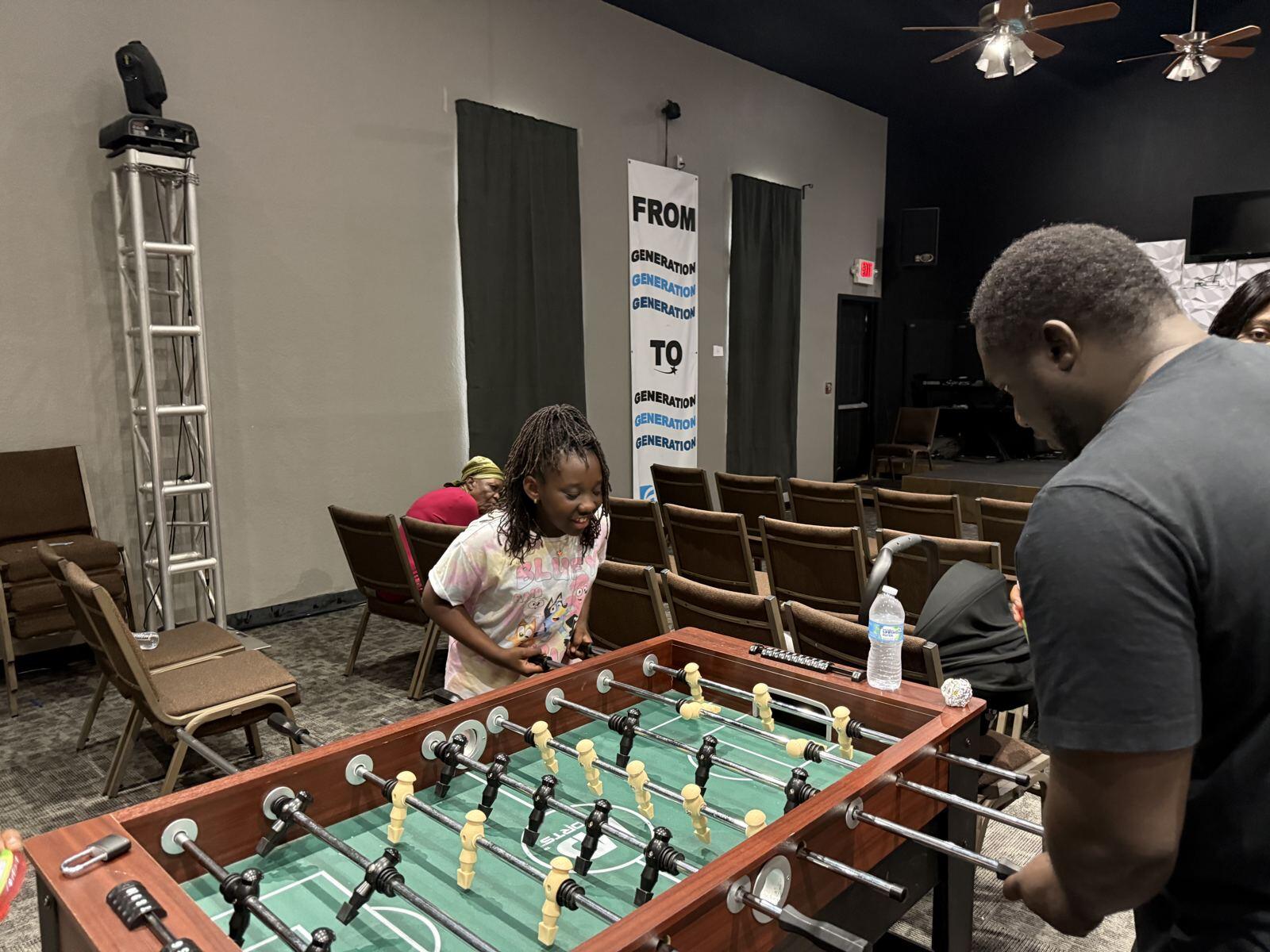 A girl and a dad playing foosball