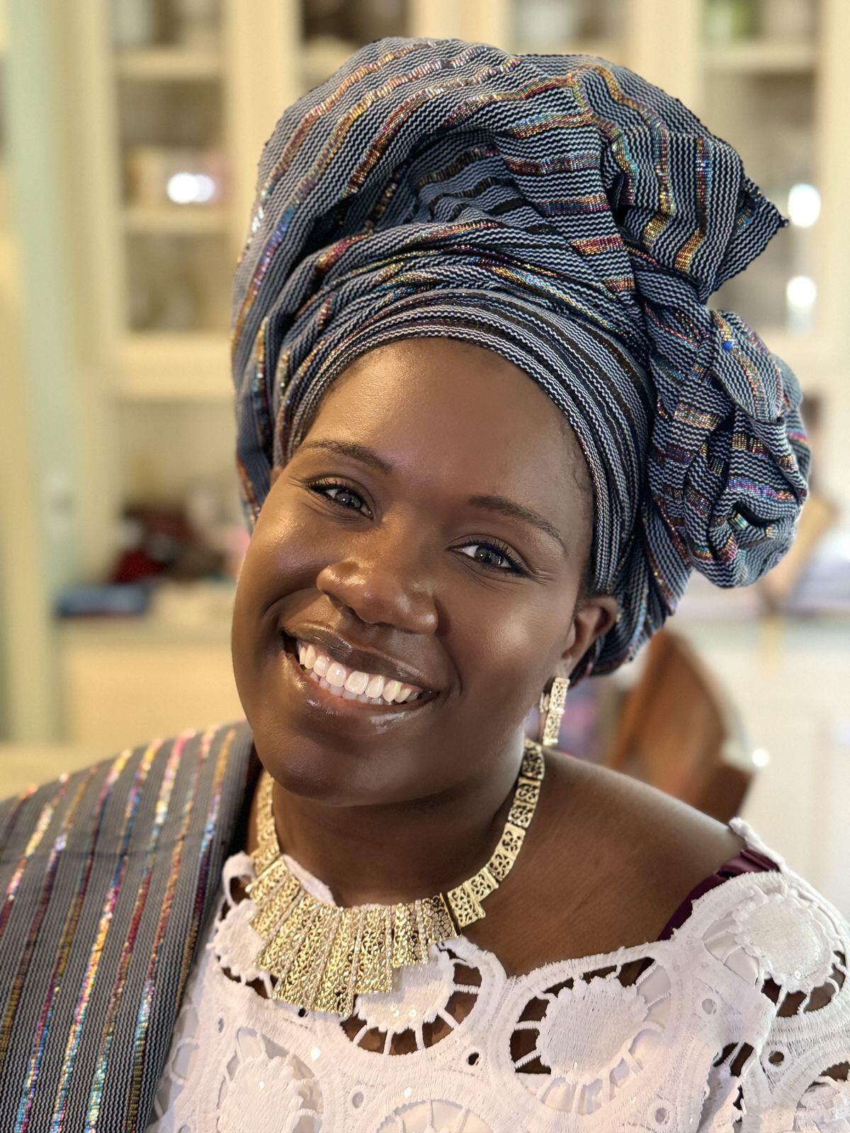 A smiling woman in a blue gele